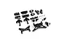 A collection of black anodized aluminium RC car upgrade parts including suspension arms, shock towers, and hardware on a white background.