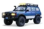 A blue 1/10 scale FMS Toyota Land Cruiser 80 Pro RC rock crawler with off-road tires, roof rack, and illuminated lights against a white background.