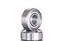 Close-up of two small metal shielded ball bearings stacked on top of each other against a white background.
