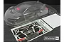 Unpainted clear polycarbonate RC car body shell for 1/8 scale GT3, including a rear wing, decal sheet, and window masks on a dark surface.