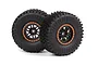 Two black rubber RC off-road tires mounted on black 12-spoke rims with orange beadlock-style rings, isolated on a white background.