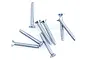 A cluster of eight silver-coloured metal countersunk head screws with coarse threads arranged on a white background.