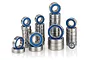 A collection of various sized metal ball bearings with blue rubber seals arranged in stacks on a white background.