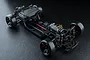 A high-angle studio shot of an assembled MST FRX S 1/10 scale RC drift car chassis on a black textured surface.