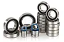 A collection of various sized metal ball bearings with black and blue rubber seals arranged on a white background.