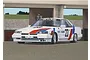An illustration of a white 1986 Nissan Skyline RS Turbo race car with red and blue racing stripes and the number 23 parked in a pit garage.
