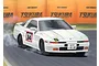 An illustration of a white 1985 Toyota Supra drifting on a racetrack with Tsukuba branding in the background.