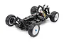 A high-angle studio shot of a Tamiya DB01SR 1/10 scale 4WD RC buggy chassis, showing the black frame, suspension, motor, and off-road tires.