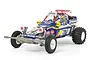 A studio shot of the Tamiya Fighting Buggy 2014 RC car, a blue 2WD off-road buggy with white wheels, racing decals, and a driver figure.