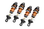 Four Traxxas orange aluminium mini GTR long shock absorbers with white springs arranged in a row against a white background.