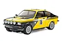 A studio shot of a Tamiya 1/10 scale RC Opel Kadett GT/E rally car model, painted yellow and black with racing decals and rally lights.
