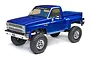 Axial SCX10 III Base Camp 1/10 scale RC rock crawler featuring a blue 1982 Chevrolet K10 pickup truck body on a white background.