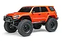 An orange Axial SCX24 Toyota 4Runner RC rock crawler viewed from a front three-quarter angle on a white background.