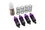 A set of four purple aluminium RC shock absorbers with black springs, plus four extra black springs and a bottle of Yeah Racing silicone damper oil.