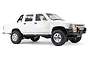 A white 1/16 scale WPL D64 Hilux RC rock crawler pickup truck viewed from the side against a white background.