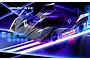 A sleek, black XRAY X12 RC pan car with orange and white racing decals, displayed in a studio setting with dramatic blue and purple neon lighting.