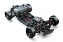 A high-angle studio shot of an MST FRX RS 1/10 scale RC drift car chassis kit, showing the black frame, red shocks, and motor mounted in the front.