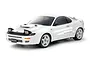 A studio shot of a white Tamiya Toyota Celica GT-Four ST185 1/10 scale RC car model with pop-up headlights and white wheels against a white background.