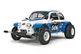 A Tamiya Sand Scorcher 1/10 scale RC buggy, featuring a white and blue body with racing decals, off-road tires, and a front bumper.