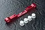 A red anodized aluminium MST suspension arm pin mount with four white plastic suspension inserts on a dark textured surface.