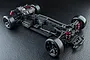 High-angle studio shot of an MST RMX 4 S Pro 1/10 scale RWD RC drift car chassis, featuring a black frame, red shock absorbers, and brushless motor.