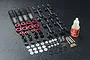 A set of unassembled MST RC drift shock absorbers with red aluminium components, springs, plastic parts, and a bottle of mineral oil on a black surface.