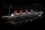 A 1/700 scale plastic model of the RMS Titanic illuminated with internal LED lights against a black background.