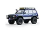 A blue FMS FCX10 Toyota Land Cruiser LC80 RC rock crawler with a roof rack, off-road tires, and bull bar, shown in a studio setting.