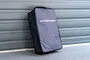 A black and grey Koswork carrying bag for 1/8 scale RC cars standing upright against a grey roller door.