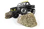 A black 1/18 scale HPI Venture18 RC rock crawler truck with a Toyota Hilux body, positioned on top of two large rocks against a white background.