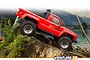 A red HPI Venture 18 RC rock crawler truck driving over a mossy tree stump in a forest setting.