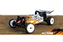 Maverick MiCROBE 1/24 scale RC buggy in orange and silver livery, viewed from a front three-quarter angle on a textured ground surface.