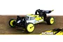 Maverick MiCROBE 1/24 scale RC buggy in yellow and white, featuring black wheels and a rear wing, positioned on a textured brown surface.