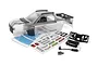 A clear, unpainted polycarbonate body shell for the Maverick 1/16 QBit MT RC truck, including a decal sheet, plastic accessories, and mounting hardware.