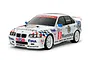 A Tamiya 1/10 scale RC BMW 318i STW touring car model with white body, Warsteiner and Fina racing liveries, and white multi-spoke wheels.