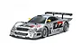A studio shot of a 1/10 scale Tamiya Mercedes-Benz CLK-GTR RC car in silver with Warsteiner racing livery and a large rear wing.