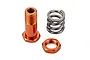 An orange anodized aluminium servo saver post, a matching orange nut, and a steel coil spring on a white background.