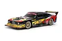 A 1/10 scale Tamiya Ford Capri Turbo RC car model with a black, yellow, and red Zakspeed racing livery, featuring gold mesh wheels and a rear wing.