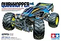 An illustration of the Tamiya Quirkhopper GF-02 1/10 scale RC monster truck, featuring a blue and black body, large off-road tires, and yellow wheels.