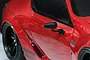A close-up of a black side mirror mounted on a red 1/10 scale RC car body shell.