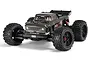 Studio shot of the ARRMA Outcast 4X4 BLX 4S RC stunt truck in gunmetal grey, featuring large off-road tires and a detailed pickup truck body.