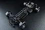 Top-down view of the MST RMX 4 GT competition-level RC drift car chassis, featuring a carbon fiber frame and black components on a textured black background.