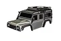 A silver Traxxas TRX-4 Land Rover Defender RC body shell with a black roof rack and fender flares against a white background.