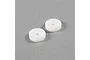 Two white circular RC shock pistons with two holes each, resting on a grey surface.
