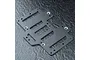 A black FRP battery mounting plate for an RC car, featuring multiple cutouts and countersunk mounting holes, set against a textured dark background.