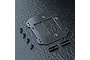 MST carbon fibre battery mount plate with four screws and two cylindrical metal posts on a dark textured background.