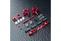 A set of red anodized aluminium RC rear hubs and associated hardware including turnbuckles, ball ends, and spacers on a dark textured surface.