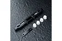 MST black aluminium adjustable lower suspension arm mount with white plastic inserts and a small black metal plate on a textured dark surface.