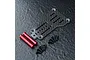 MST carbon fiber rear link plate with two red aluminum posts and several small black screws on a textured black surface.