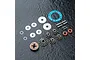 A set of MST limited slip differential parts including metal gears, washers, pins, O-rings, and a blue gasket on a dark textured surface.